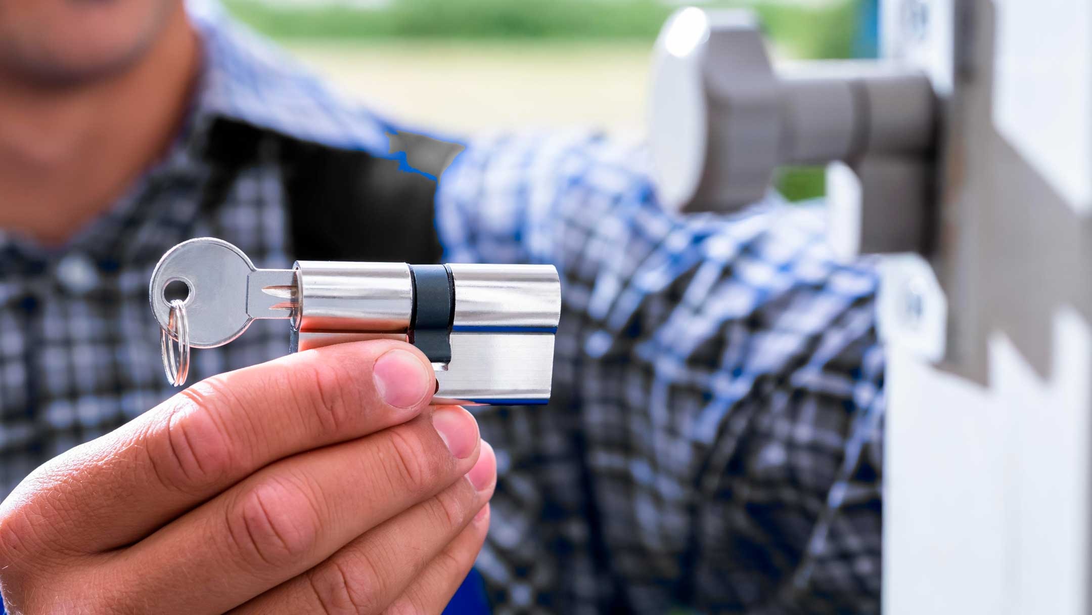 Mano sosteniendo bombín de cerradura nuevo con llave