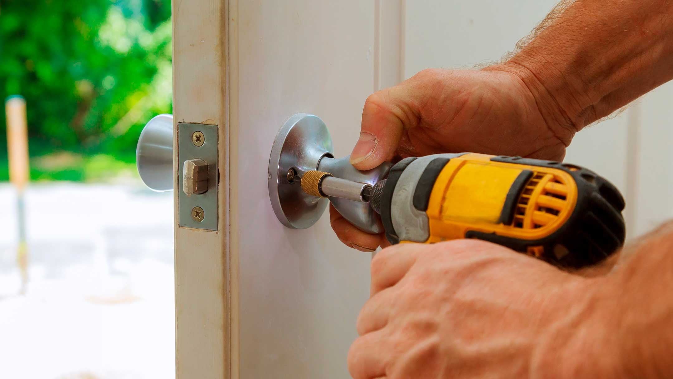 Cerrajero profesional usando taladro en cerradura de puerta